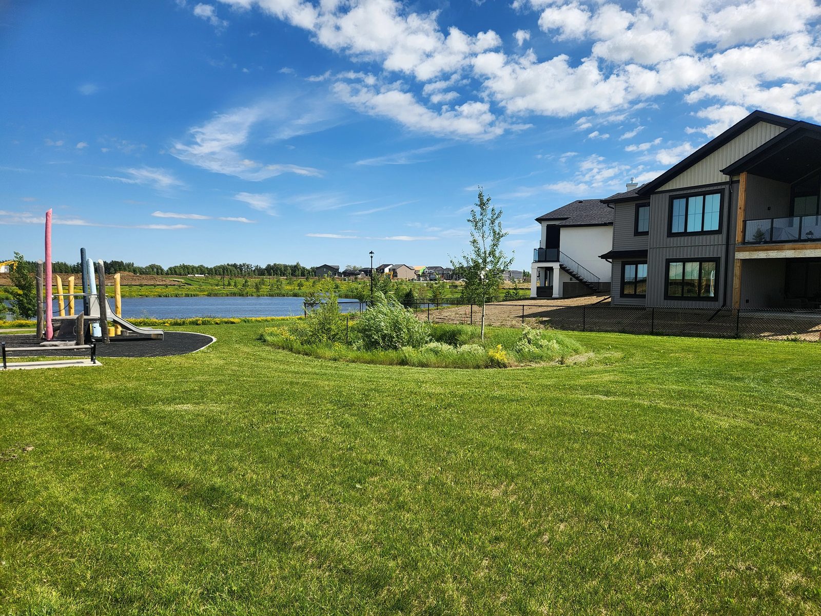 Playground and pond with a custom walkout home in Élan, Beaumont